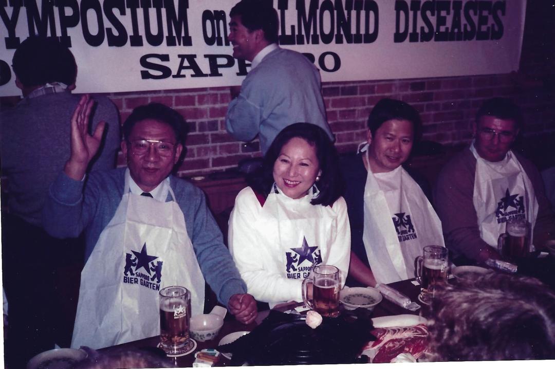 Four individuals sitting at a Japanese restaurant table wearing food garments.