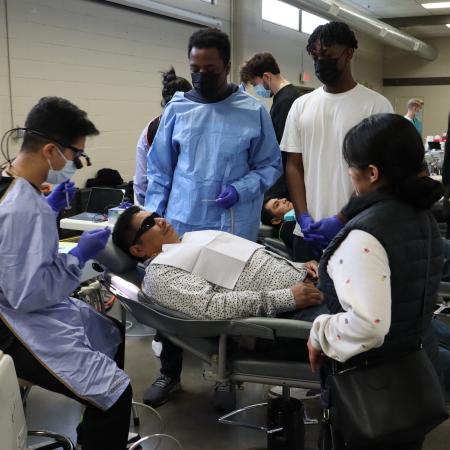 Students help a community member receive dental care.