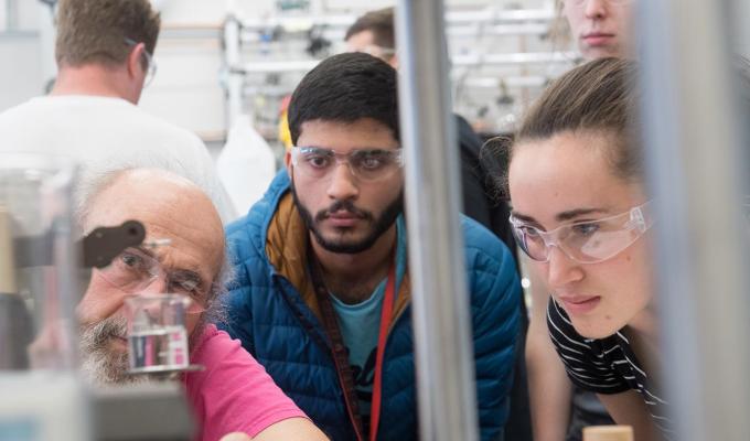 Science students with professor looking at experiment in lab