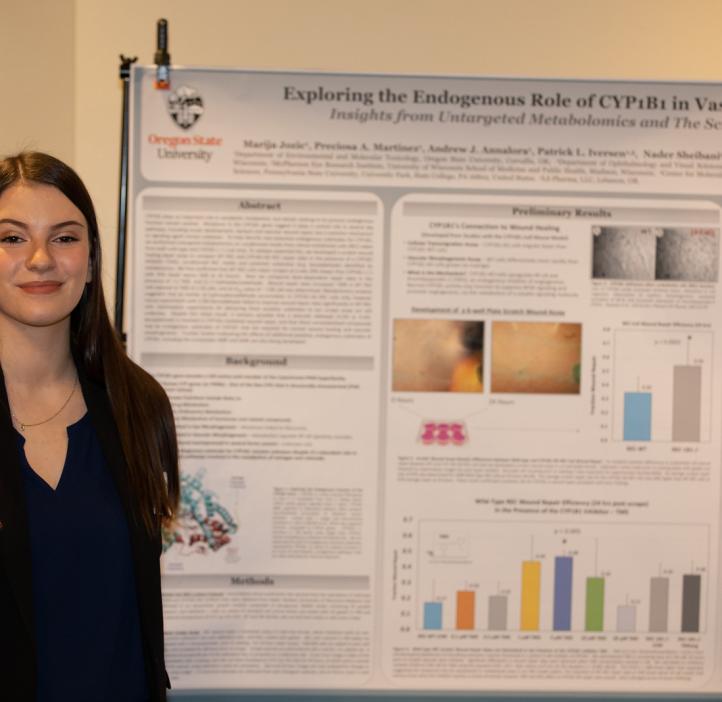 student standing next to her research poster